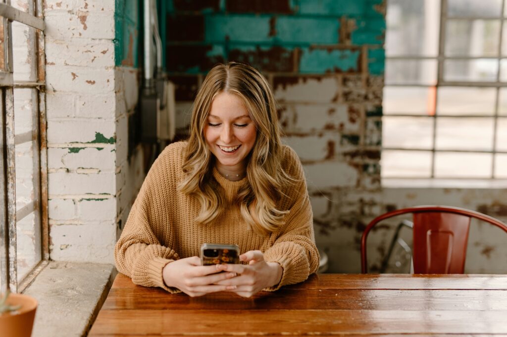 woman sitting at table looking at phone